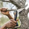 A person is using a folding saw to cut a tree branch. Produktbild-Vorschau
