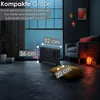A black electric convector heater is shown in a dimly lit room with a large window, a chair, and decorative lighting. Produktbild-Vorschau