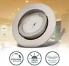 A close-up of a recessed LED spotlight with three circular icons below it, each displaying a feature of the product. The background shows a blurred interior of a room with ceiling lights. Produktbild-Vorschau