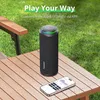 A black outdoor speaker and a smartphone are placed on a wooden table in a grassy area. Náhľad obrázku produktu