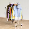 A clothing rack with various garments and a small backpack, set against a white brick wall. Anteprima dell’immagine prodotto