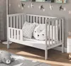 A baby bed with pillows and a stuffed animal in a nursery setting. Anteprima dell’immagine prodotto