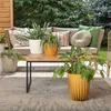 An outdoor patio setting with a couch, coffee table, and several potted plants. Voir les images du produit