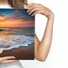 A person is holding a canvas print of a beach sunset. Podgląd zdjęcia produktu