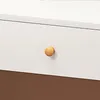 A close-up of a white drawer with a round wooden knob and a brown surface below. Podgląd zdjęcia produktu