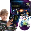 A young boy is holding a box that is part of a universe and galaxy collection set. Scattered around the box are small, round ornaments that appear to be planets. A larger globe of Earth is also visible. Náhled obrázku produktu