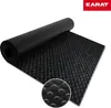 A black rubber mat with a circular pattern is rolled up and partially unrolled on a white background. A close-up inset shows the texture of the mat. Podgląd zdjęcia produktu