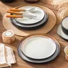 Geschirrset und silbernes Besteck auf hellem Holztisch Voir les images du produit