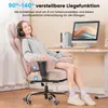 A woman is sitting in a pink gaming chair with headphones on, her eyes closed, appearing relaxed. The chair is next to a desk with a computer monitor and books. Podgląd zdjęcia produktu