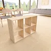 A light wood cube shelf unit is placed on a light wood floor in a modern living/dining area with large windows overlooking trees. Produktbild-Vorschau