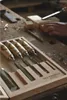 A set of chisels in a wooden case on a workbench with a person's hand in the background. Podgląd zdjęcia produktu