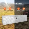 A silver aluminum truck tool box is shown in an outdoor setting, split between a sunny landscape and a rainy scene with a truck in the background. Text highlights its weather-resistant features. Anteprima dell’immagine prodotto