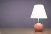A table lamp on a wooden surface against a purple wall. Podgląd zdjęcia produktu