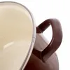 A close-up view of the handle and rim of a brown and cream pot. Voir les images du produit
