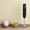 A black H.Koenig hand blender is displayed on a wooden surface next to a bowl of soup and a small white container. Anteprima dell’immagine prodotto