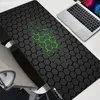 A large gaming mousepad with a hexagonal pattern and green accents is shown on a desk next to a laptop. Náhled obrázku produktu