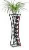 A plant sits atop a tall, black metal wine rack filled with red wine bottles. Podgląd zdjęcia produktu