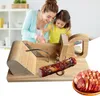 A mother and daughter are in a kitchen, using a wooden sausage slicer. Náhled obrázku produktu