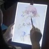 A person is using a light pad to trace an anime-style drawing of a girl and a dog. Náhled obrázku produktu