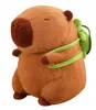 A stuffed toy capybara with a small green backpack. Produktbild-Vorschau