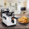 A deep fryer and a plate of french fries on a wooden table, with a blurred kitchen background. Anteprima dell’immagine prodotto
