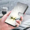 A hand holding a phone case with a lotus flower design, with a coffee cup and a notebook in the background. Produktbild-Vorschau