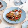 A table setting with plates of food, including a slice of cake and a pizza-like dish, with cutlery and a napkin. Náhled obrázku produktu