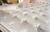 A close-up view of a white mattress with a tufted surface and intricate patterns. Produktbild-Vorschau