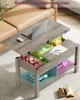 A coffee table with its top lifted to reveal storage compartments, showing various items inside. Voir les images du produit