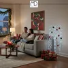 A couple sits on a couch in a living room decorated for Christmas, with a lit tree and gifts. Podgląd zdjęcia produktu