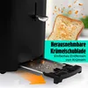A close-up of a black toaster with a crumb tray being pulled out, and a slice of toast flying out of the toaster with crumbs. Anteprima dell’immagine prodotto