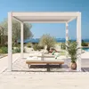 A white pergola with louvred roof stands over two lounge chairs on a patio with a pool and ocean in the background. Náhled obrázku produktu