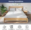 A mattress on a wooden bed frame, with bedside tables and a plant. Produktbild-Vorschau