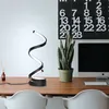 A modern desk setup with a spiral LED lamp, a plant, and a computer monitor. Podgląd zdjęcia produktu