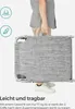 A person is holding a folded gray lounger. Produktbild-Vorschau