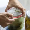 Hands are shown sealing a glass jar with a red-ringed lid, with another jar visible in the background. Anteprima dell’immagine prodotto