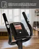 Close-up of the console of an exercise bike with a smartphone mounted on it, displaying a music app. The background shows a blurred interior of a room. Produktbild-Vorschau