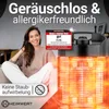A woman is sitting on a couch next to a heater. Produktbild-Vorschau