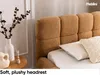 A close-up view of a plush, textured headboard of a bed, with pillows and a vase with branches in the foreground. Produktbild-Vorschau