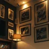 A corner of a room with framed pictures on the wall and a lamp. Anteprima dell’immagine prodotto