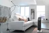A modern living room with a white sectional sofa, a floor lamp, and a black electric heater. Anteprima dell’immagine prodotto