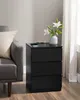 A black nightstand with three drawers is placed next to a gray sofa. Náhled obrázku produktu