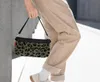 A person is holding a small leopard-print pouch bag. Produktbild-Vorschau