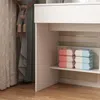 A close-up view of a white vanity table with shelves holding stacks of pink and blue items, possibly makeup wipes or similar products. Curtains are visible in the background. Náhled obrázku produktu