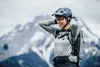 A woman wearing a helmet and backpack in a mountainous environment. Produktbild-Vorschau