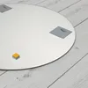A round mirror with mounting hardware on a light wooden floor. Produktbild-Vorschau