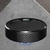 A black robotic vacuum cleaner is shown on a gray carpet with a hint of wooden flooring in the background. Produktbild-Vorschau