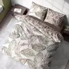 A bed with a duvet and pillows featuring a leaf pattern, placed in a bedroom setting with a nightstand. Anteprima dell’immagine prodotto