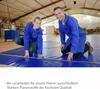 Two people in blue work uniforms are measuring a large blue tarp in a warehouse. Produktbild-Vorschau