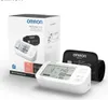 A product shot of an Omron M6 Comfort AFIB upper arm blood pressure monitor and its packaging. Produktbild-Vorschau